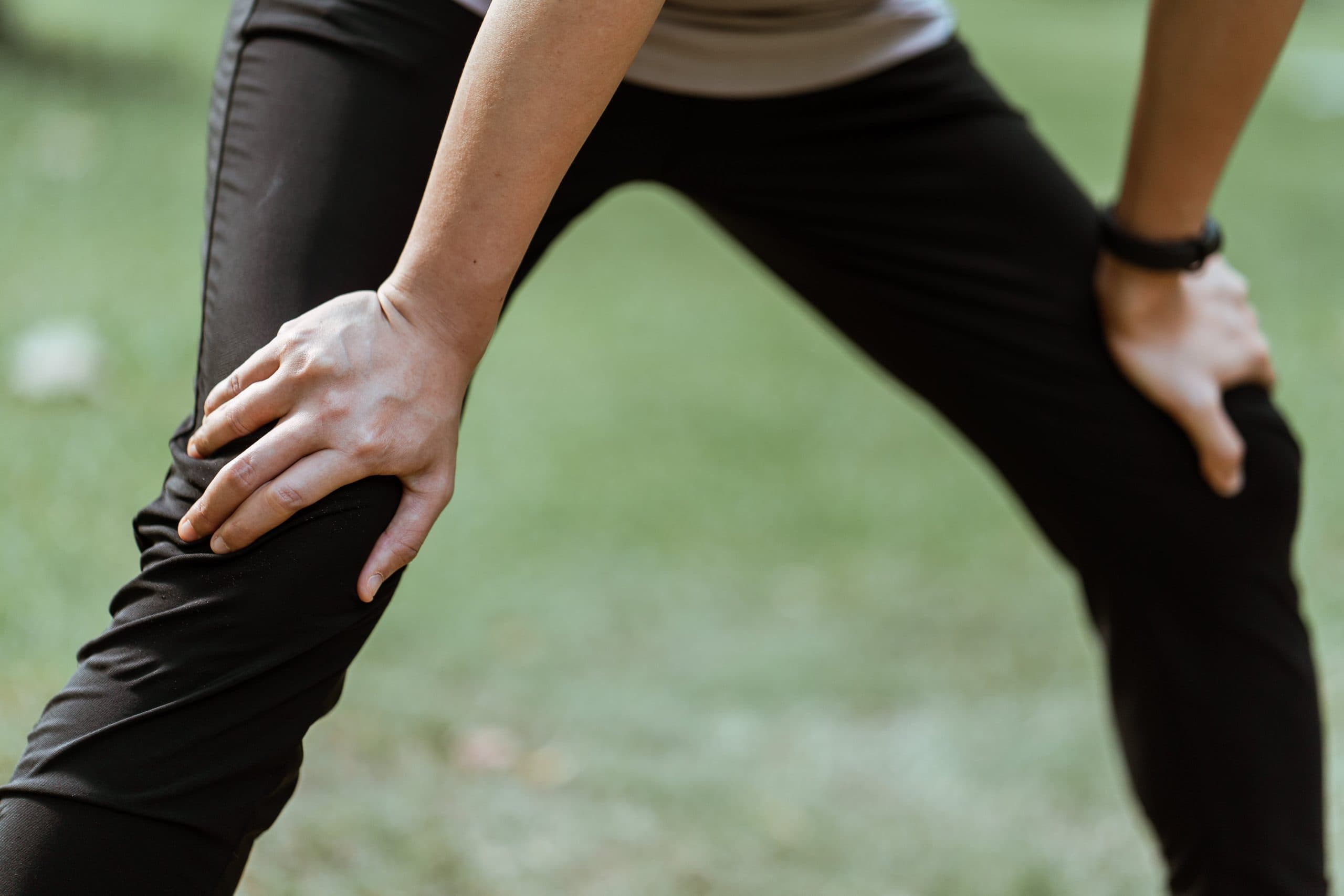 Athlete stretching outdoors with focus on knee discomfort